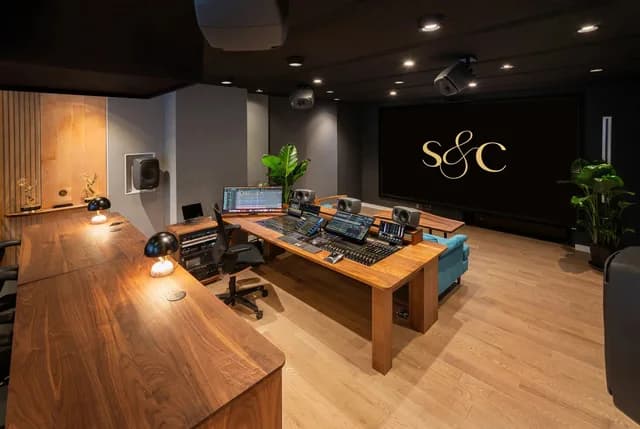 Studio A’s mix position, projection screen and producer seating, with overhead monitoring and wood finishes.