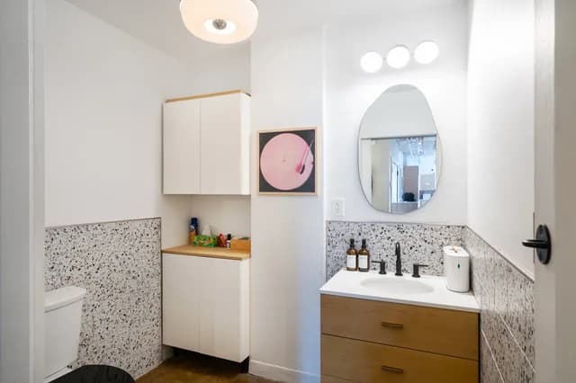 The facility’s bathroom, with terrazzo finishes, wood cabinetry and wall lighting.