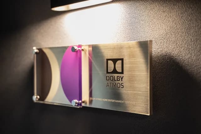 The Dolby Atmos Home Entertainment certification plaque beside a sconce in the sound lock.